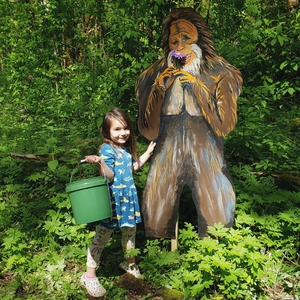 young girl posing next to sasquatch with litter picker in her hand